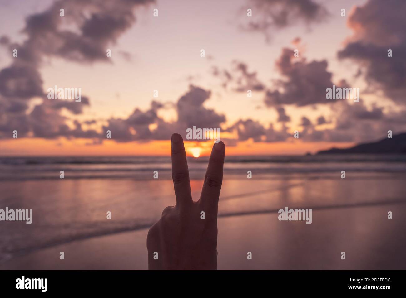 Frau Hand tun Frieden heraus mit Sonnenuntergang Strand Hintergrund. Stockfoto