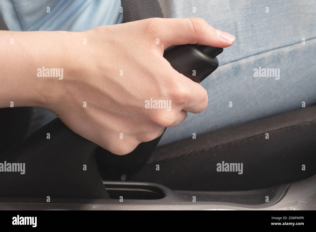 Weibliche Hand drückt die Handbremstaste, Not-aus, Parken, Gefahr des Abrollens. Nahaufnahme, selektiver Fokus Stockfoto