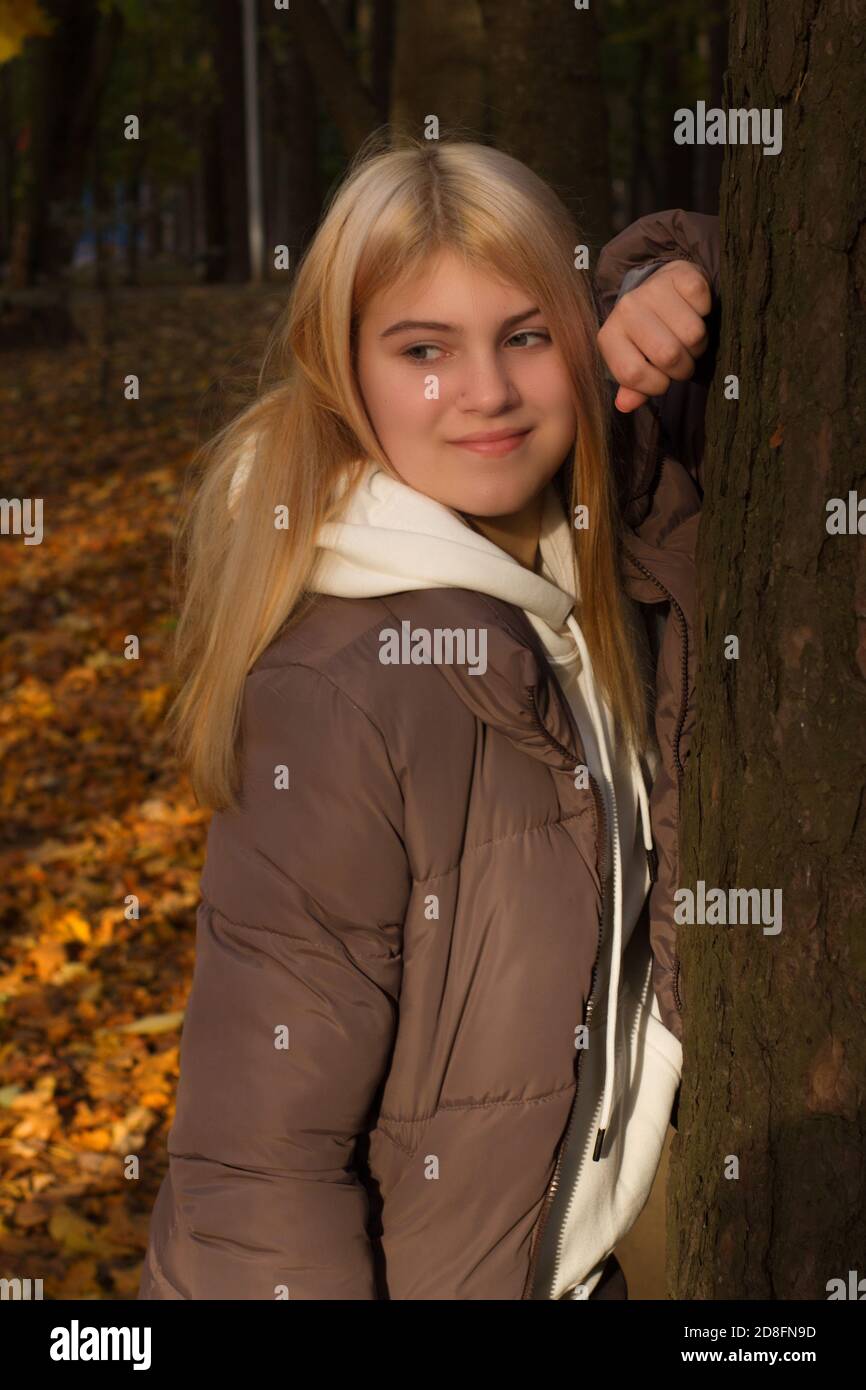 Ein junges Mädchen mit langen blonden Haaren auf einem Spaziergang in einem Herbstpark. Warme Farbe. Stockfoto