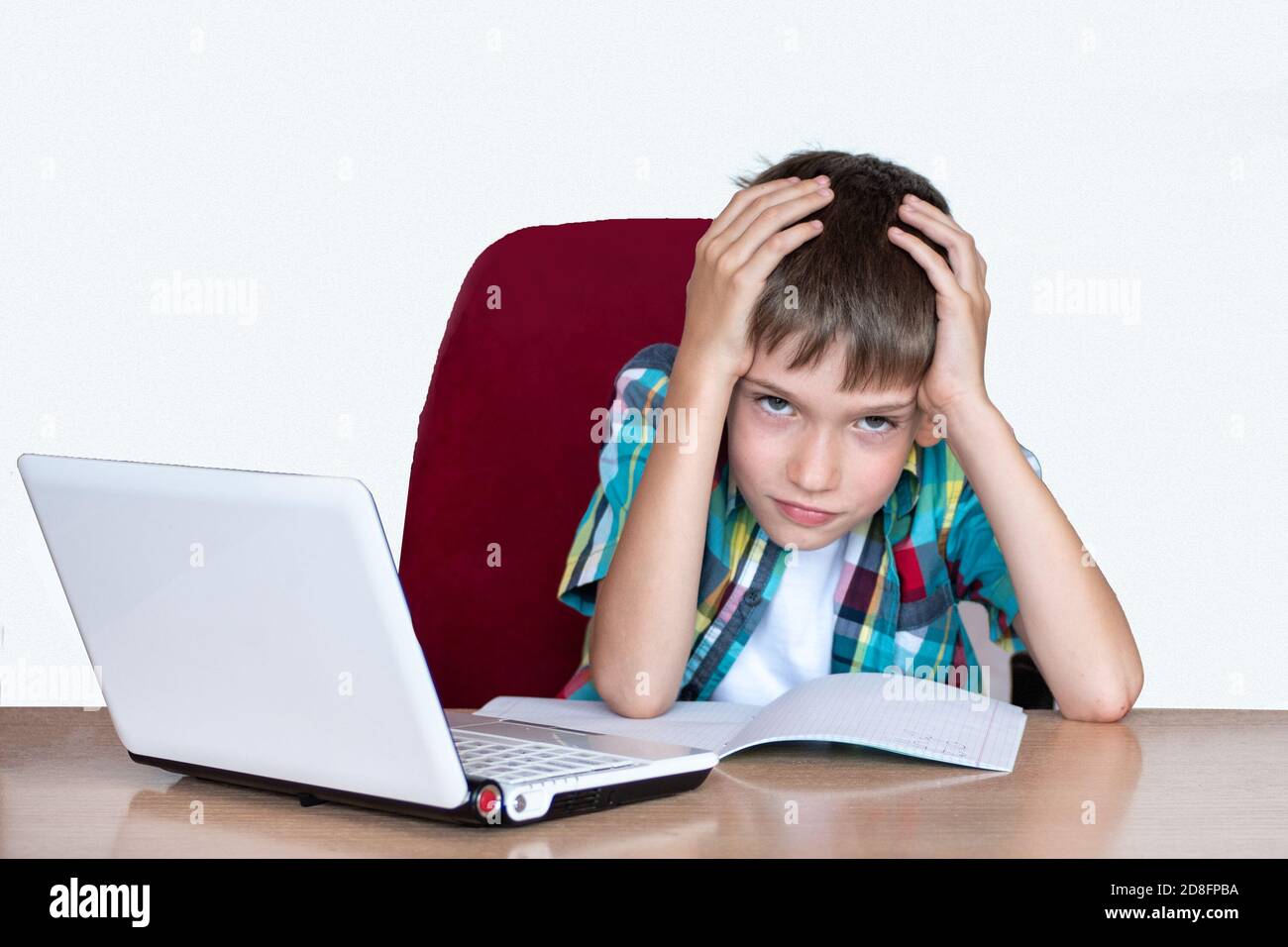 Müder Junge, der seinen Kopf hält, um Hausaufgaben zu machen. Kind mit Lernschwierigkeiten. Bildungskonzept, zurück zur Schule Stockfoto