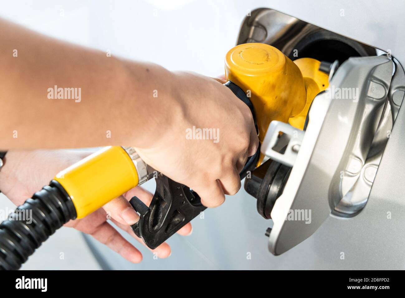 Gelbe Düse mit Handhaltung zum Tanken des Fahrzeugs bei Gas Station Stockfoto