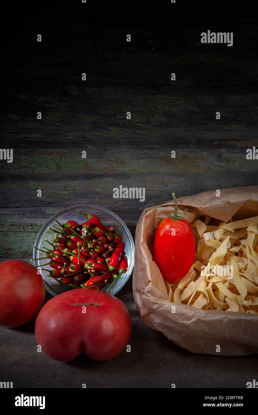 Stillleben Foto von Tagliatelle mit roten Paprika und Tomaten Auf verfallener dunkler Holzhintergrund Stockfoto