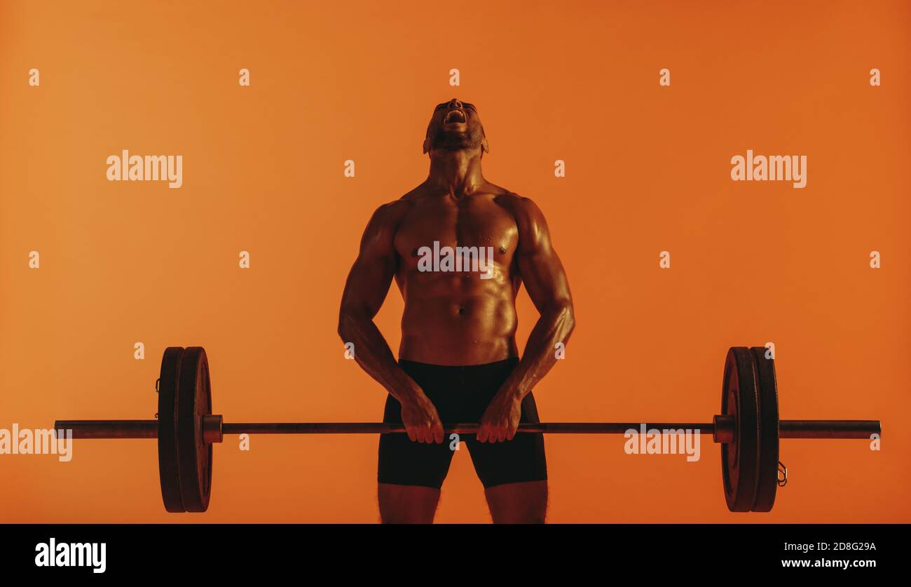 afroamerikanische Gewichtheber, der sich bemüht, die Langhantel zu heben. Muskulösen Mann dabei Krafttraining. Stockfoto