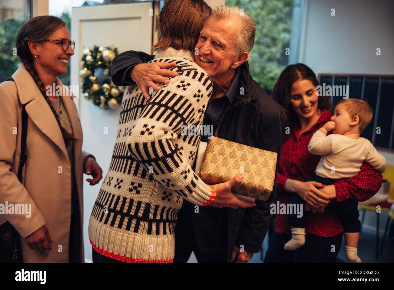 Mann begrüßt und umarmt seinen Vater vor der Tür. Europäische Familie kommt zusammen für Weihnachten festliche Feiern. Stockfoto