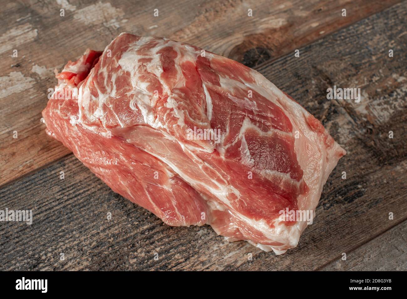 Rohes Schweinefleisch. Großes Stück Schweinefleisch Hals auf einem dunklen Holzhintergrund. Schweinefilet ist bereit zum Kochen Stockfoto