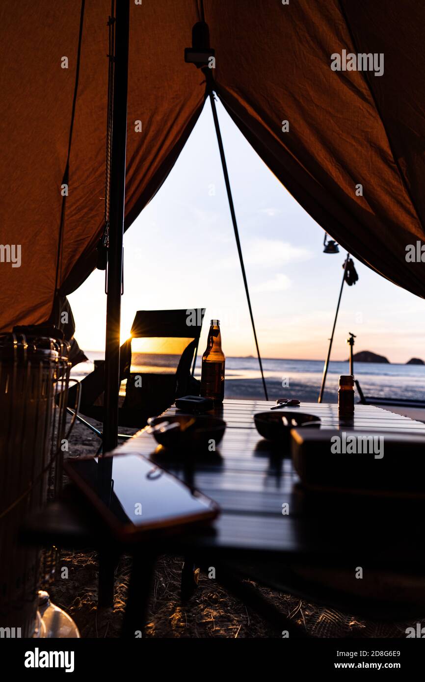 Ein gemächliches Meer. Camping mit Blick auf den Sonnenuntergang und einem Schluck Bier Stockfoto