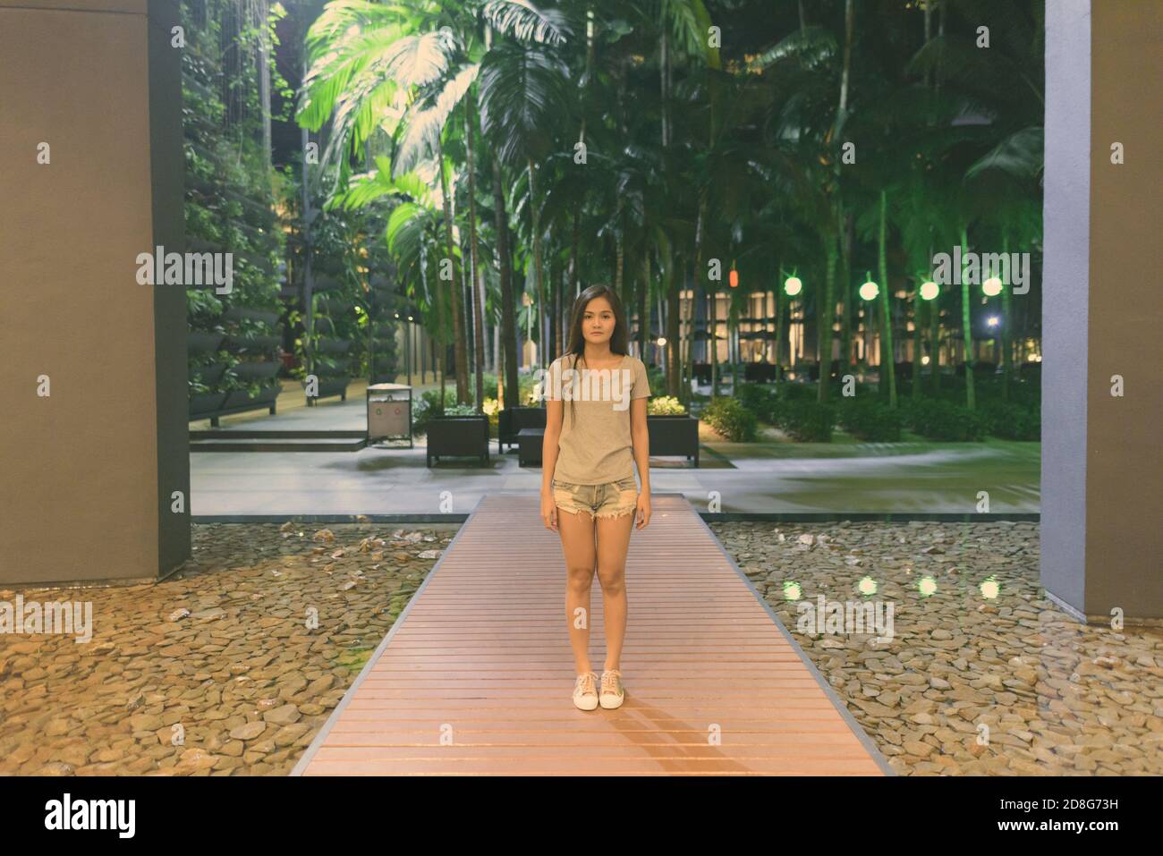 Junge, schöne asiatische Frau, die auf Holzstegen am Hoteleingang steht Stockfoto