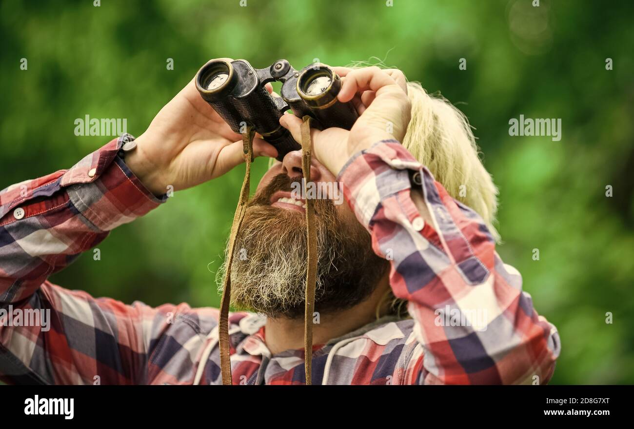 Touristen Mann mit Fernglas auf der Suche nach etwas entlang des Waldes. Mann mit Fernglas Teleskop im Wald. Reisekonzept. Weit weg in die Zukunft schauen. Hobby und Entspannung. Stockfoto