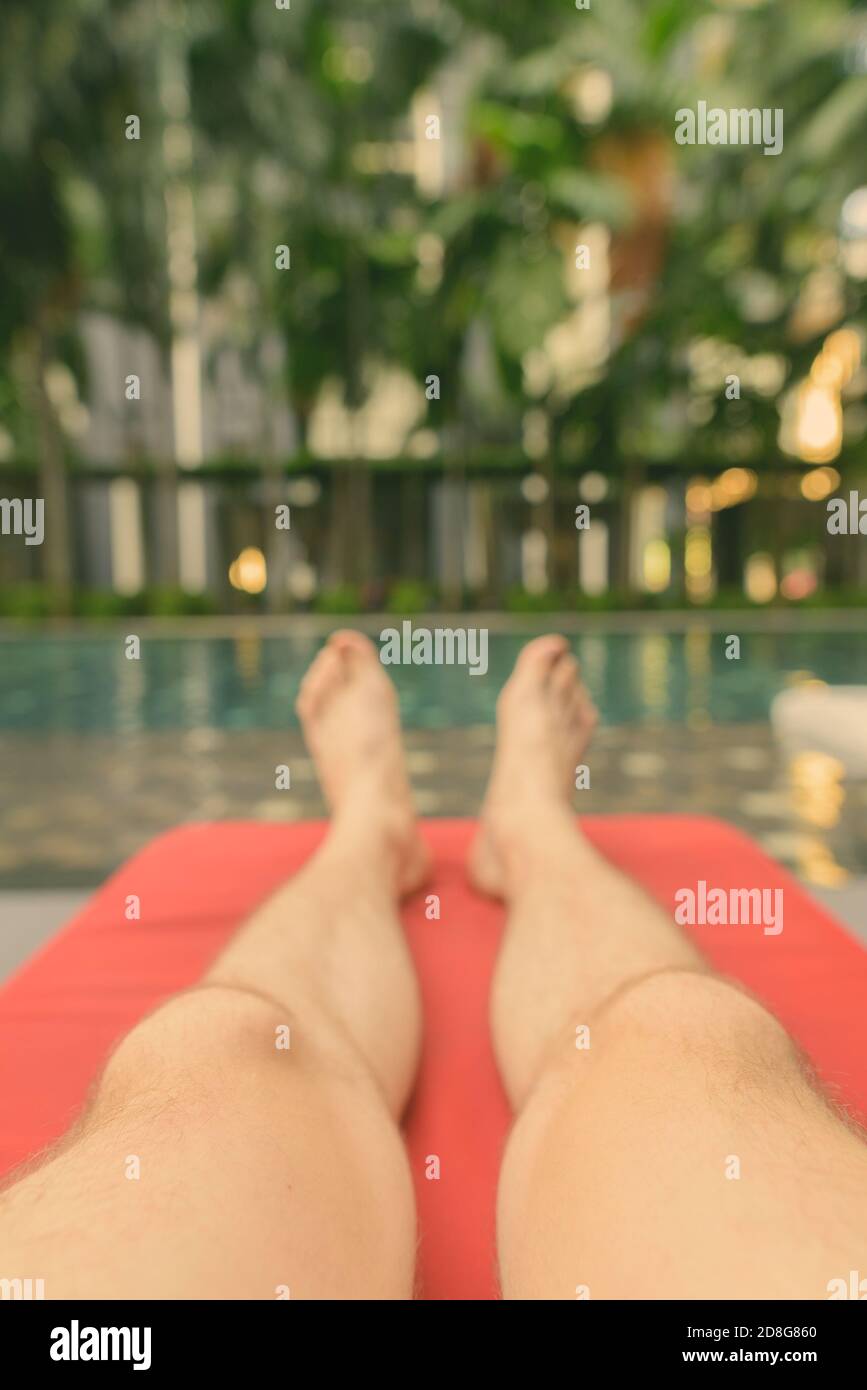 Füße eines jungen, hübschen Mannes, der sich am Swimmingpool im Hotel in Kuala Lumpur, Malaysia, entspannt Stockfoto