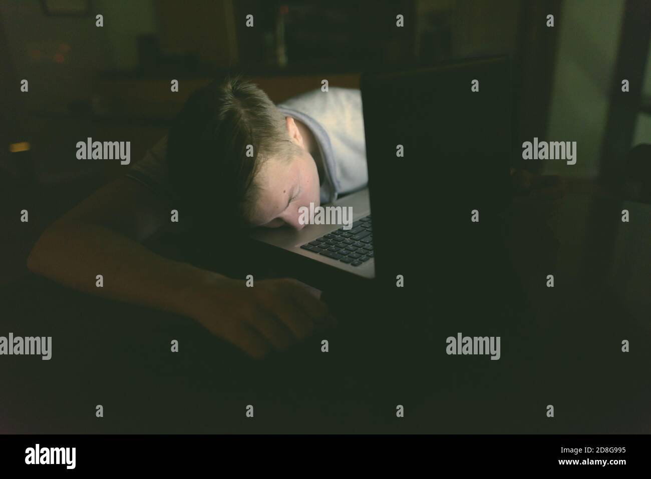 Junger stattlicher Mann mit Laptop im dunklen Wohnzimmer Stockfoto