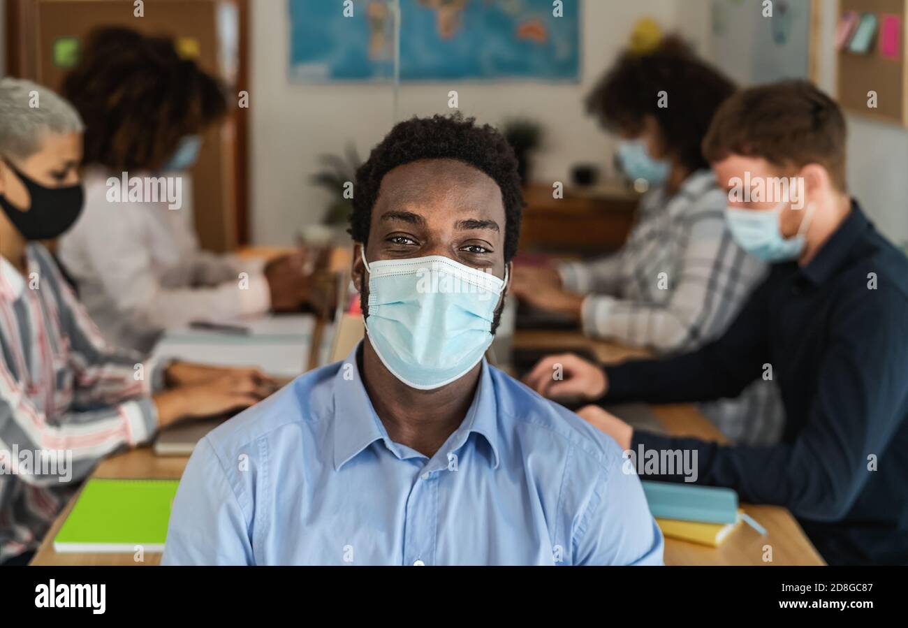 Afrikanischer Mann trägt Gesichtsmaske in Co-Working kreativen Raum mit Teamarbeit - Junge Menschen, die während einer Coronavirus-Pandemie arbeiten Stockfoto