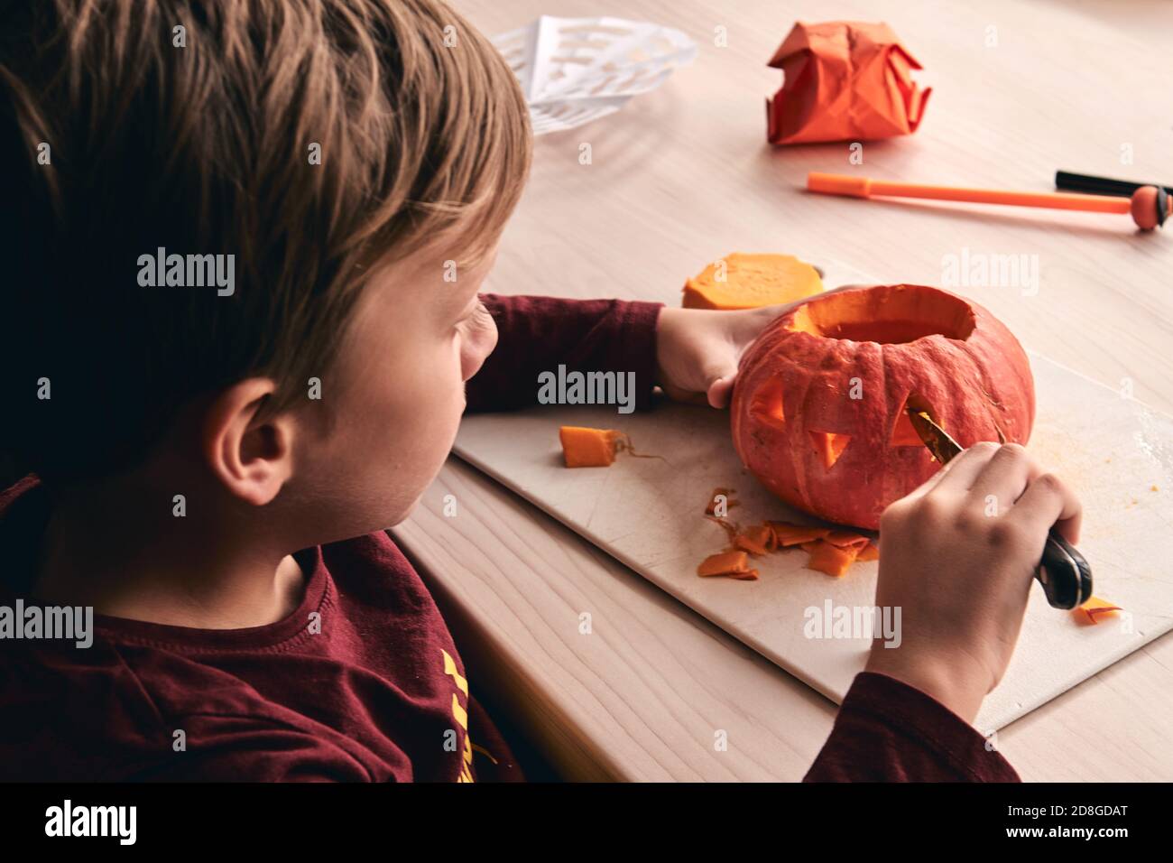 Halloween, Dekoration und Urlaub Ideen- Nahaufnahme des Kindes mit Messer Schnitzerei Kürbis oder Jack-o-Laterne. 6 Jahre junge hat Heimfamilie Spaß Aktivität. Mama Stockfoto