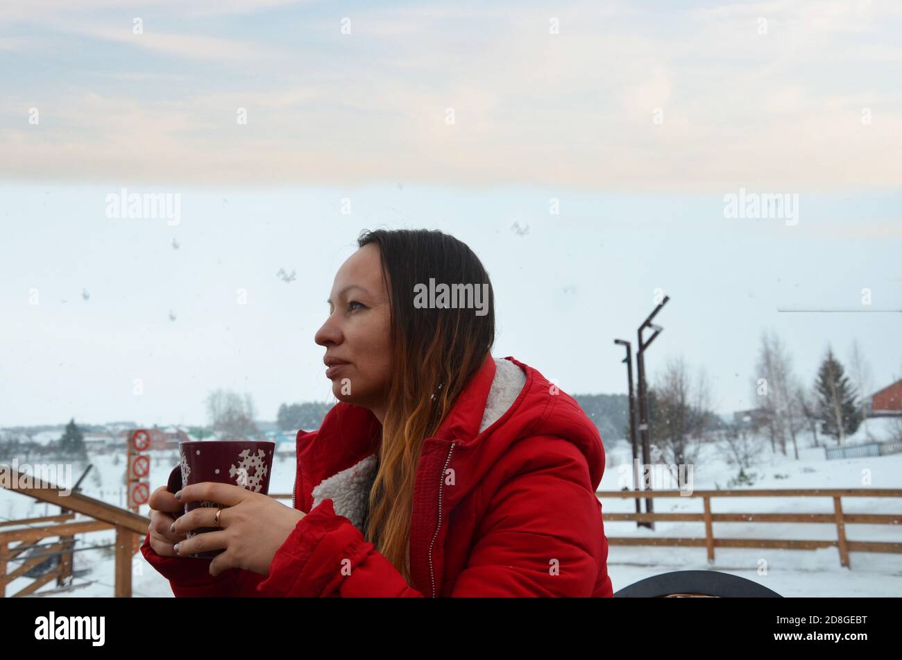 Frau trinkt heißen Tee oder Kaffee aus Festliche Tasse mit verschneiten Berg Blick auf den Hintergrund. Schönes Mädchen genießen Winter Morgen oder Abend im Freien Stockfoto