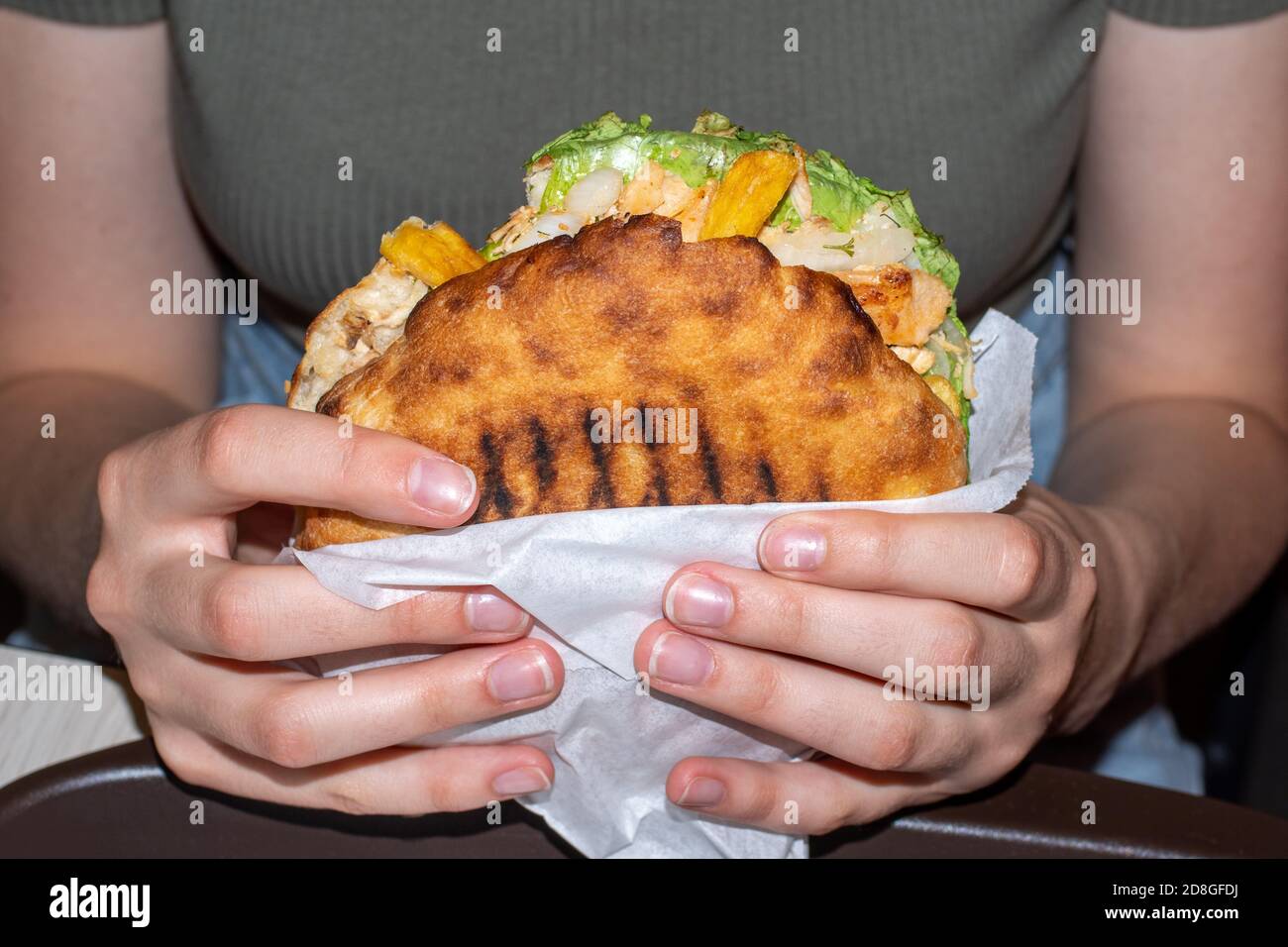 Nahaufnahme der weiblichen Hände mit einem großen Hamburger, Vorderansicht. Ungesunde Ernährung Konzept. Übergewicht Konzept Stockfoto