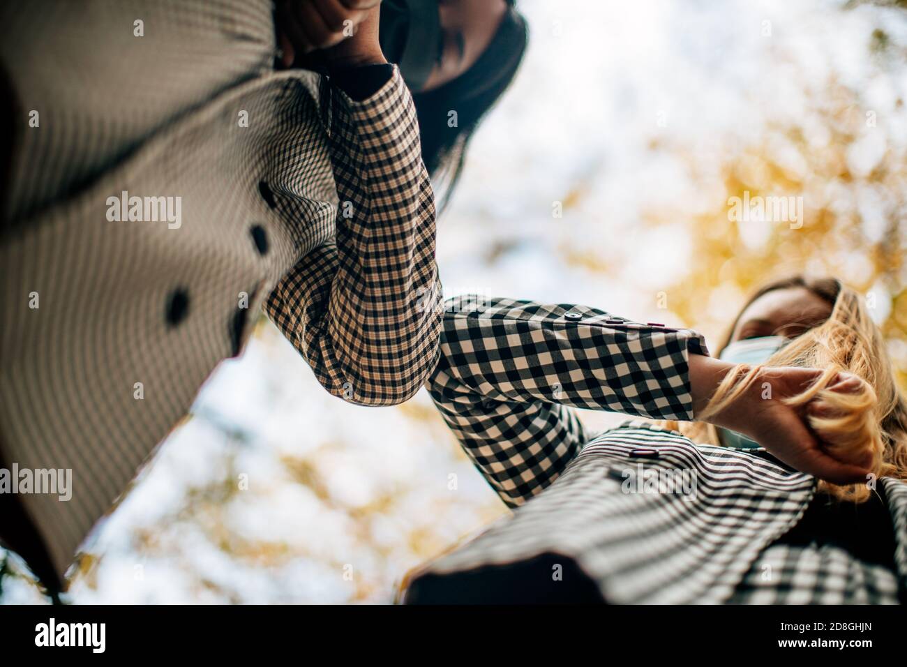 Zwei elegante Geschäftsfrauen von gemischten Rennen treffen im Freien stoßen Ellbogen statt Begrüßung mit einem Handschlag. Ellenbogen stoßen ist die neue Normalität in Pandem Stockfoto
