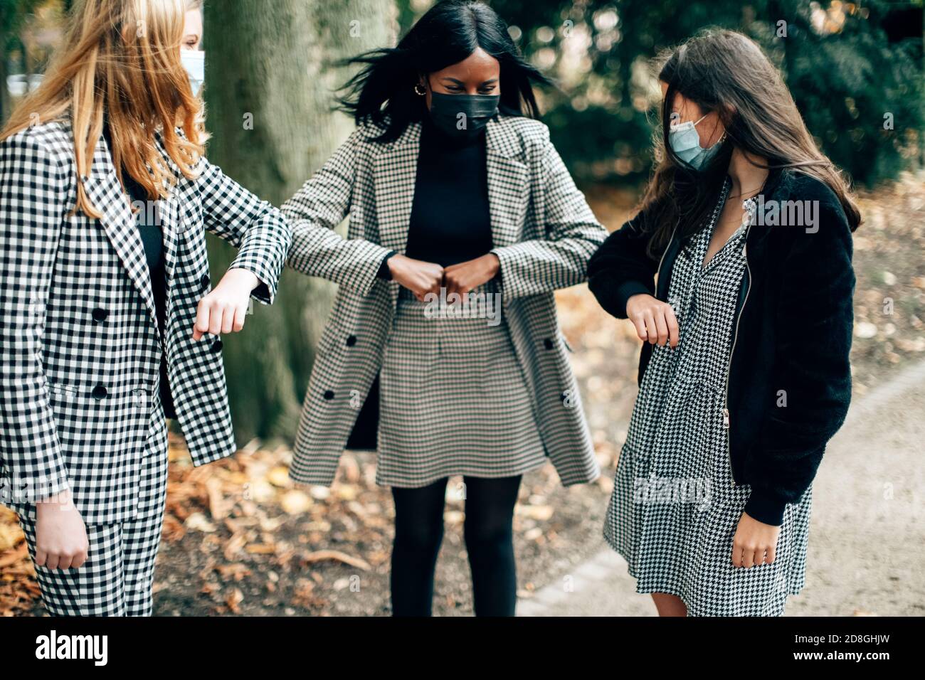 Drei Frauen tragen Gesichtsmaske Gruß mit Ellenbogen Beule. Ellenbogenstopfen ist eine neue normale Sicherheitsregel, um die Ausbreitung von Coronaviren zu verhindern. Soziale DIS Stockfoto