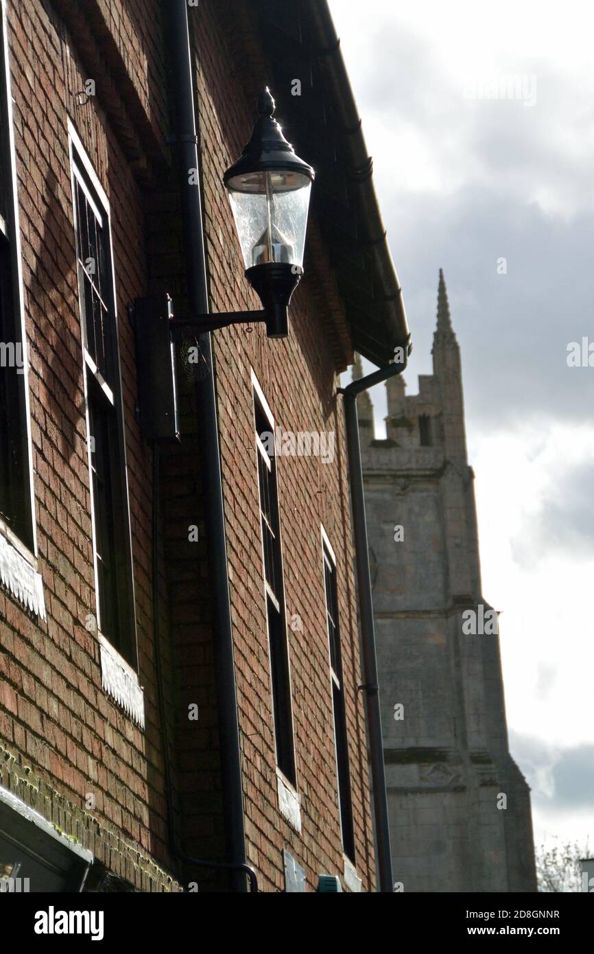 Herbstsonne auf einer wandmontierten Straßenlampe in Little Church Street, Wisbech, Cambridgeshire, mit dem Kirchturm von St. Peter und St. Paul dahinter Stockfoto