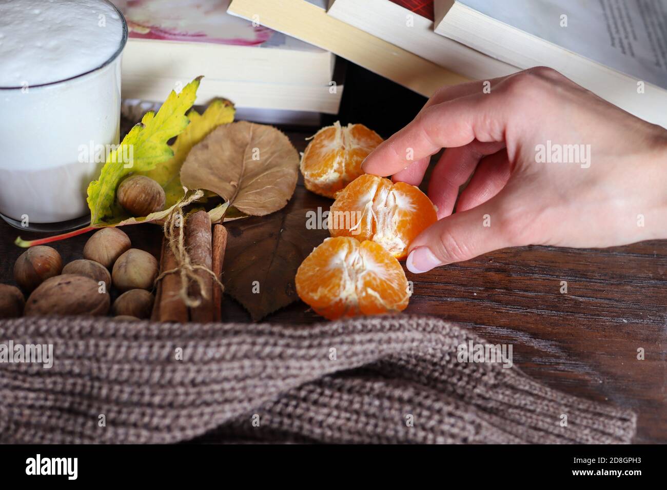 Frau nimmt orangene Früchte mit der Hand vom dekorierten Schreibtisch im Herbstkonzept. Gesunde Ernährung Konzept Stockfoto