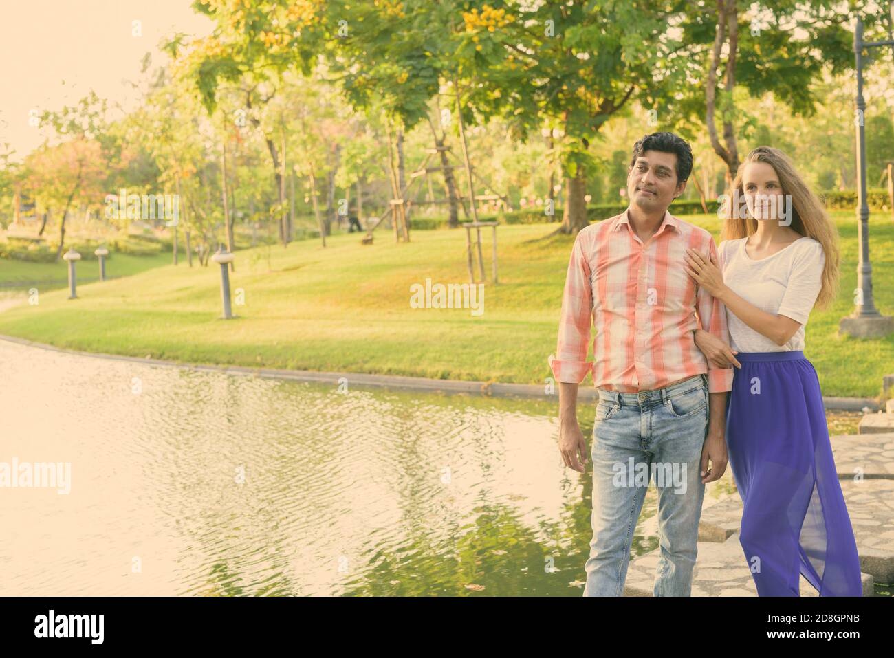 Multi-ethnische Paar denken beim Stehen auf Stein Pfad in der Mitte des Sees in einer ruhigen, grünen Park Stockfoto