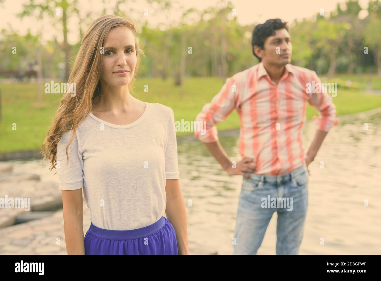 Schöne Frau mit indischen Mann denken und stehen auf Stein Pfad in der Mitte des Sees in einer ruhigen, grünen Park Stockfoto