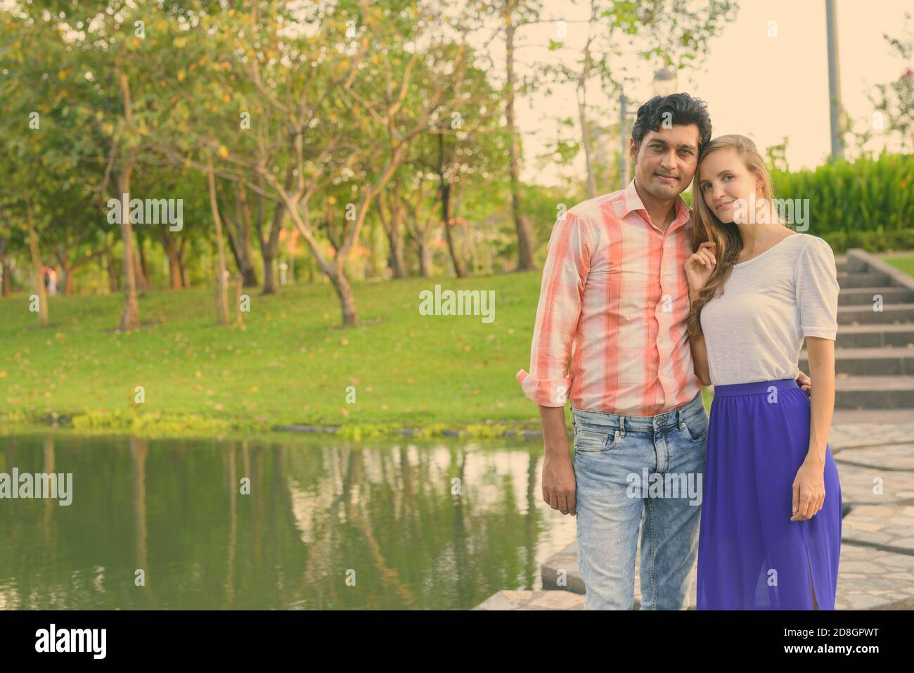 Multi-ethnische Paar stehen auf Stein Pfad in der Mitte des Sees mit Blick auf die ruhigen, grünen Park Stockfoto