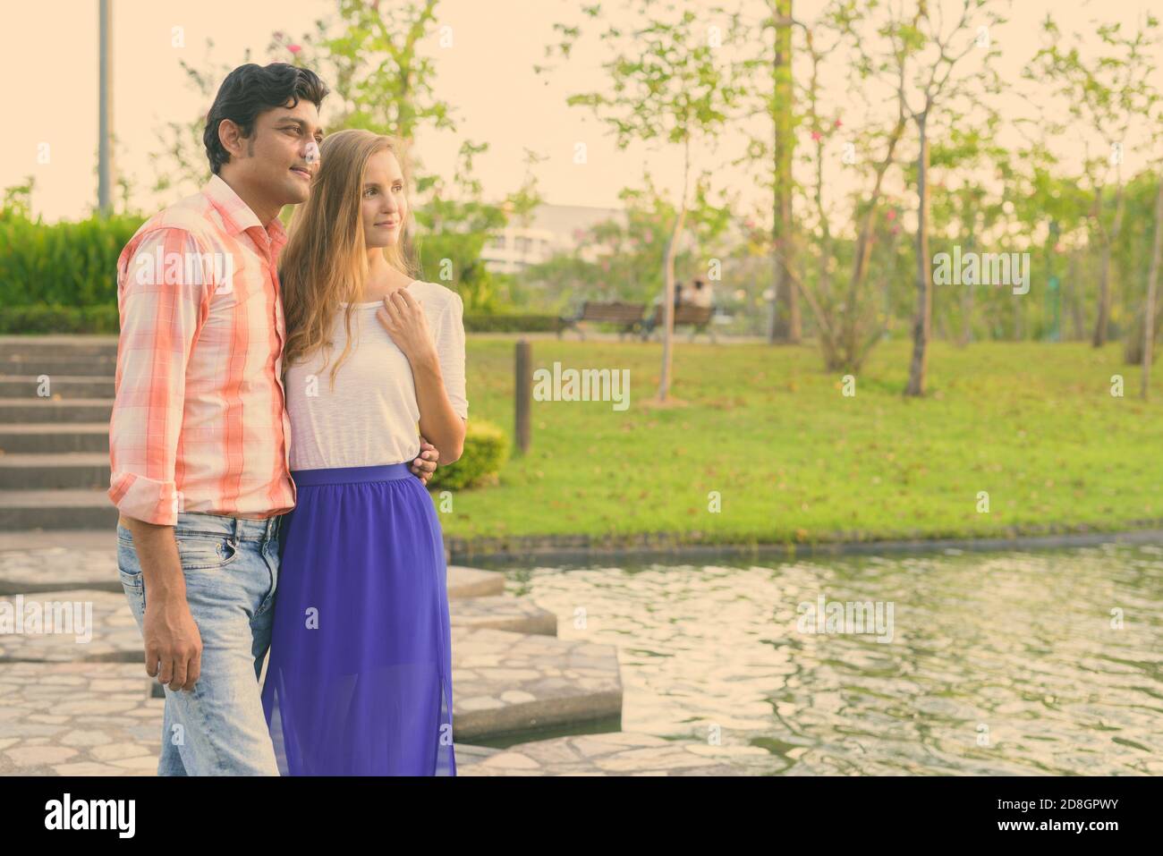 Multi-ethnische Paar stehen und Denken auf Stein Pfad in der Mitte des Sees mit Blick auf die ruhigen, grünen Park Stockfoto