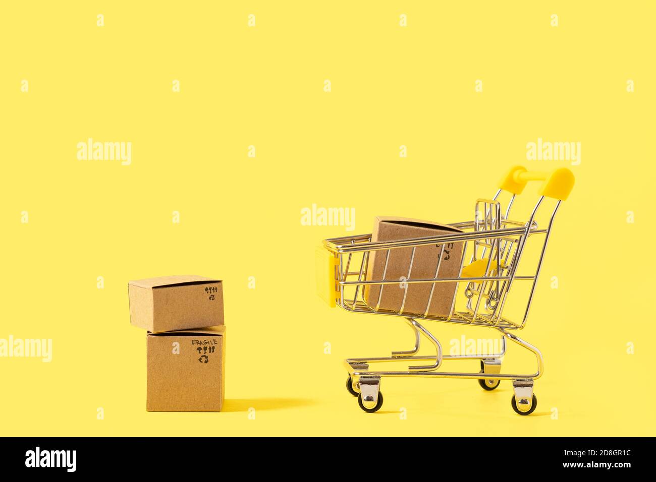 Spielzeug-Warenkorb mit Schachteln auf gelbem Hintergrund. Platz für Text oder Design kopieren. Verkaufs-, Rabatt-, Einkaufs- und Lieferkonzept. Konsumgesellschaft Stockfoto