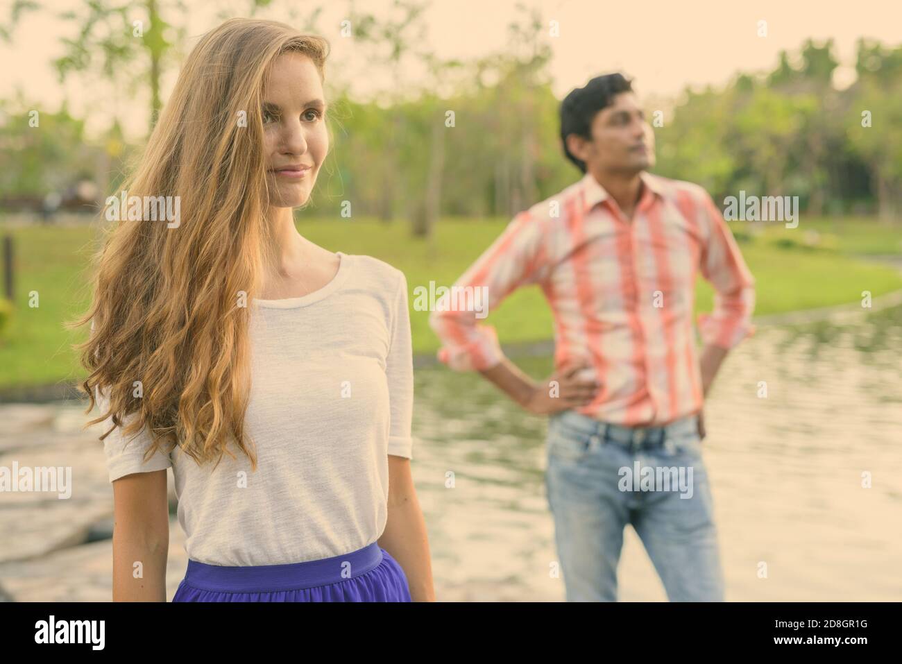 Schöne Frau denken mit indischen Mann gemeinsam auf Stein Pfad in der Mitte des Sees in einer ruhigen, grünen Park Stockfoto