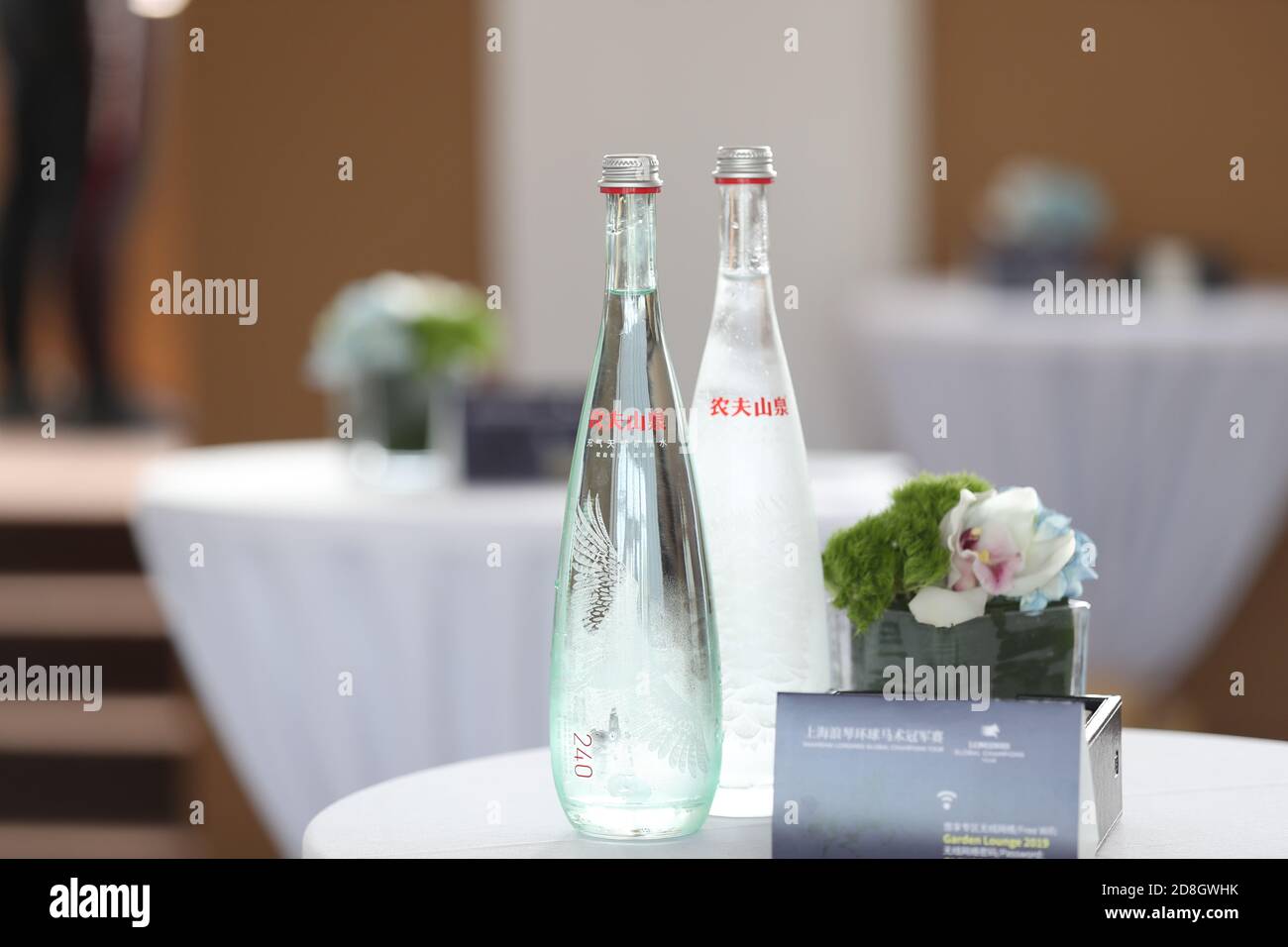 --FILE--Flaschen Wasser mit tollem Design, produziert von Nongfu Spring, einem chinesischen Unternehmen für Mineralwasser und Getränke, werden für die Teilnehmer auf den Tisch gelegt Stockfoto