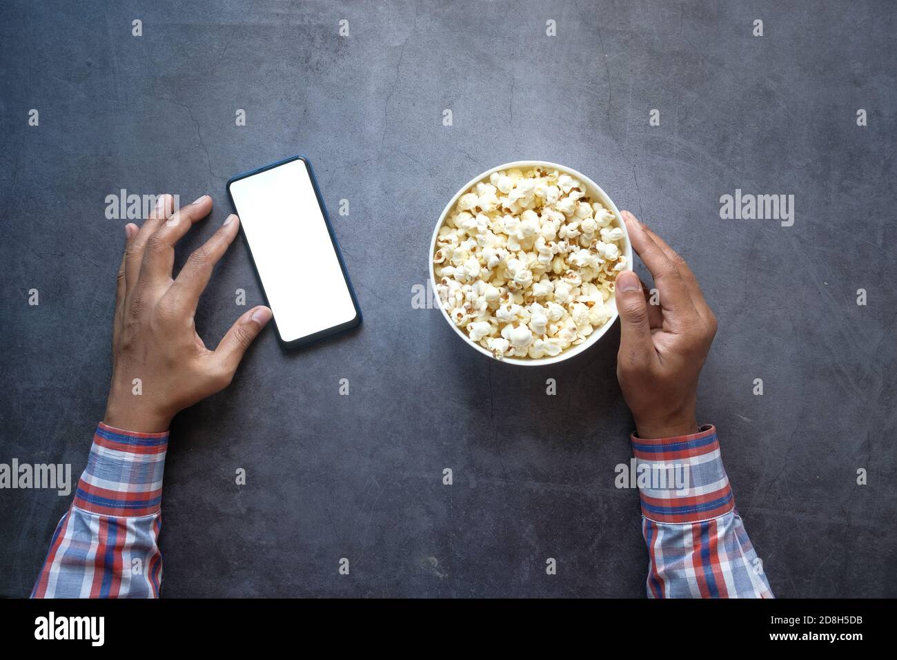 Mann Hand mit Smartphone und essen Popcorn Stockfoto