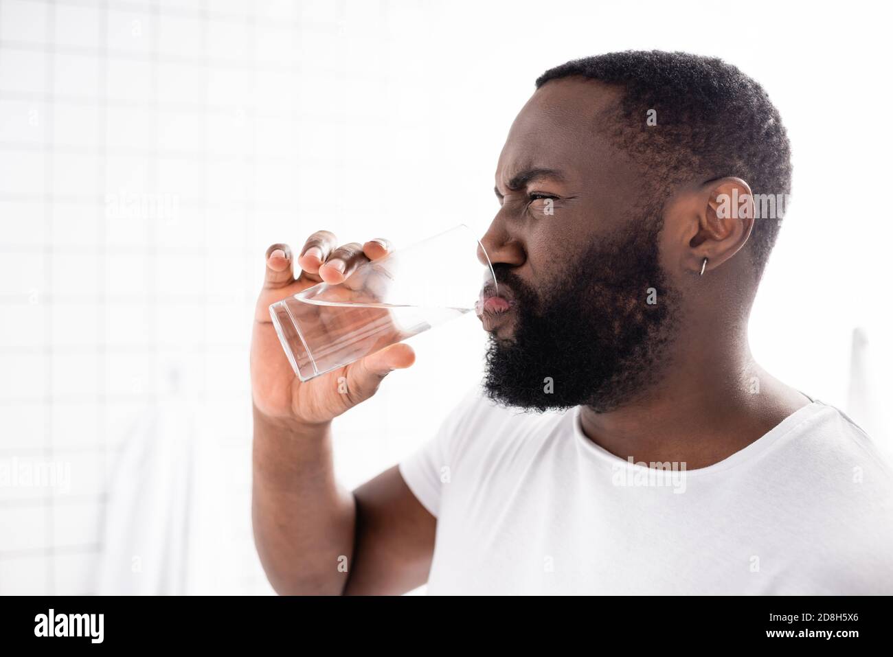afro-amerikanischer Mann Grimacing und Trinkwasser Stockfoto