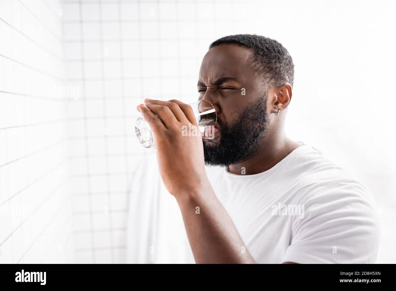afro-amerikanischer Mann Grimacing und Trinkwasser Stockfoto