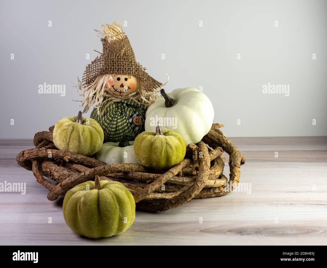 Scarecrow mit grünem Outfit und einem Burlap-Hut auf einem Holzkranz mit kleinen grünen Kürbissen, die ihn umgeben, für ein Herbst-Dekor, perfekt für Herbst A Stockfoto