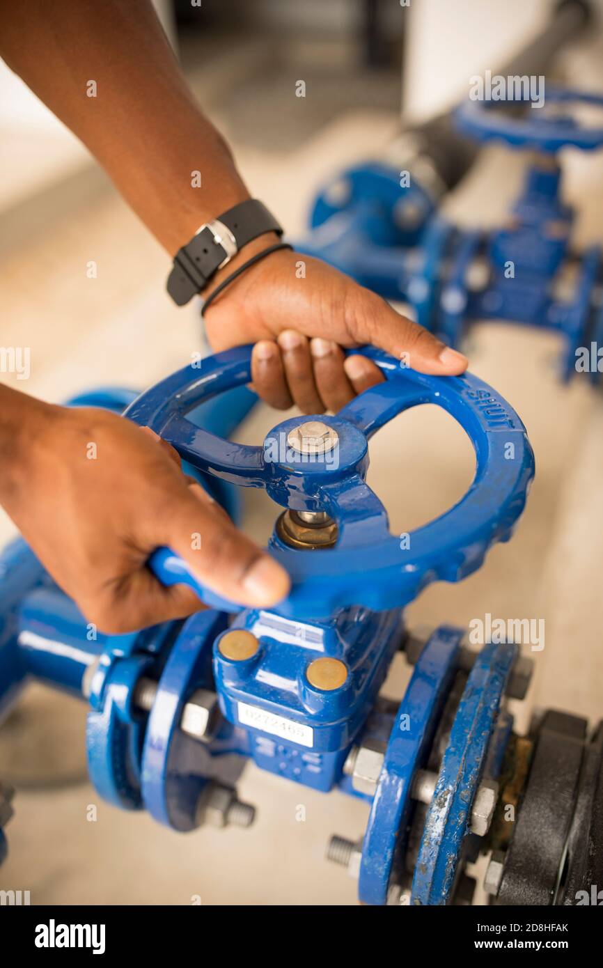 Ein professioneller Arbeiter betreibt einen neuen Ausrüstungsventil an einem Wasserreservoir und einer Pumpstation auf Maio Island, Cabo Verde. Stockfoto