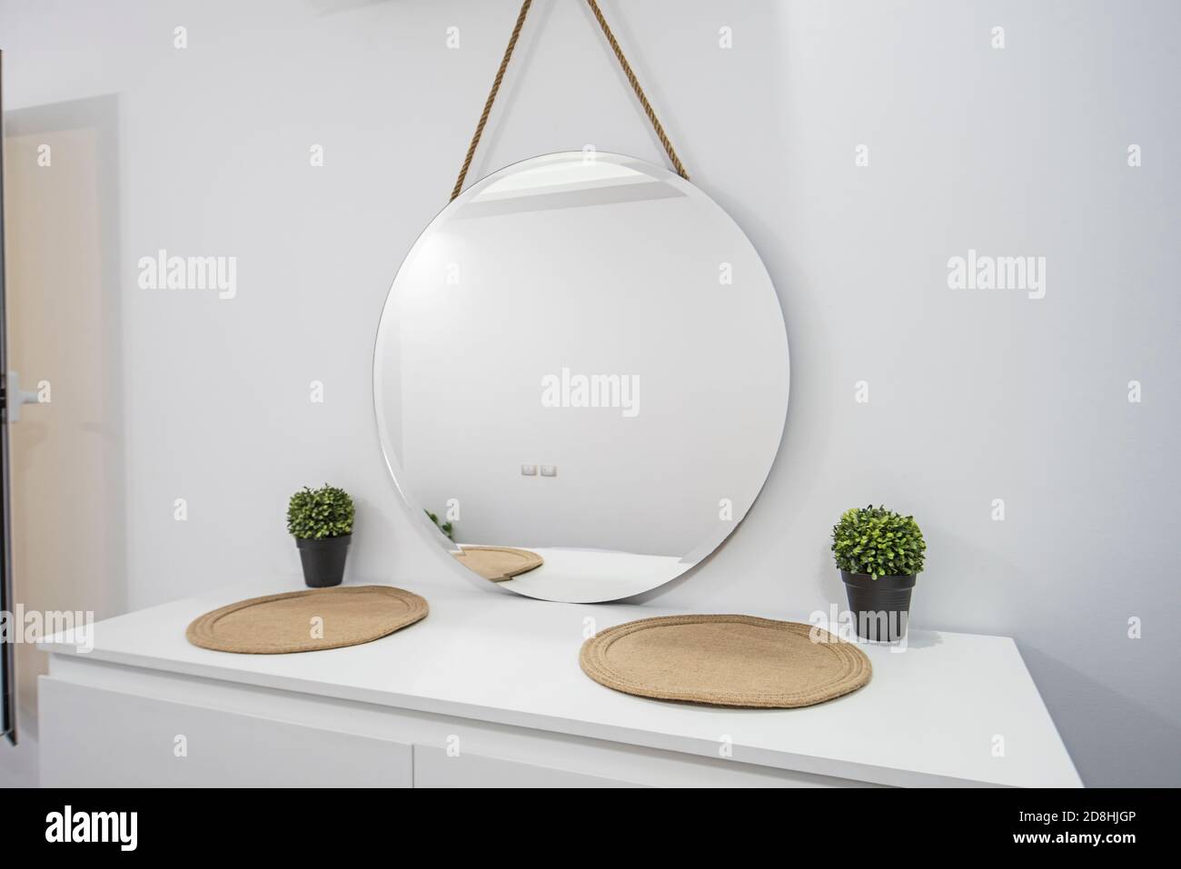 Runder runder Spiegel, der an der Wand über dem weißen Tisch hängt Einheit in Luxus-Wohnanlage Stockfoto