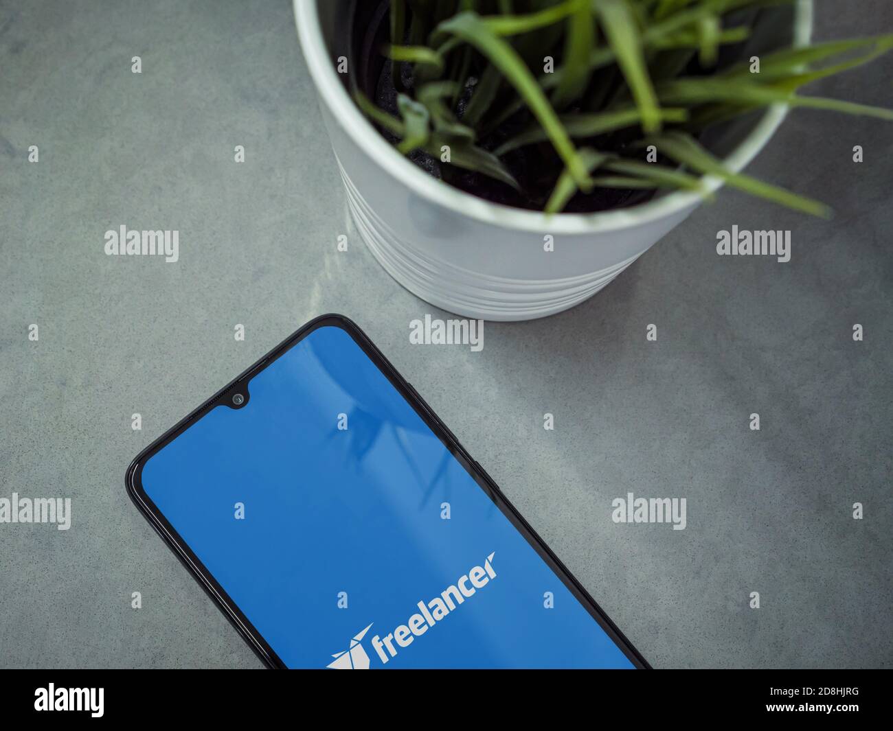 LOD, Israel - 8. Juli 2020: Moderner minimalistischer Büroarbeitsplatz mit schwarzem Smartphone mit Freelancer App Launch Screen mit Logo auf Marmorrückseite Stockfoto