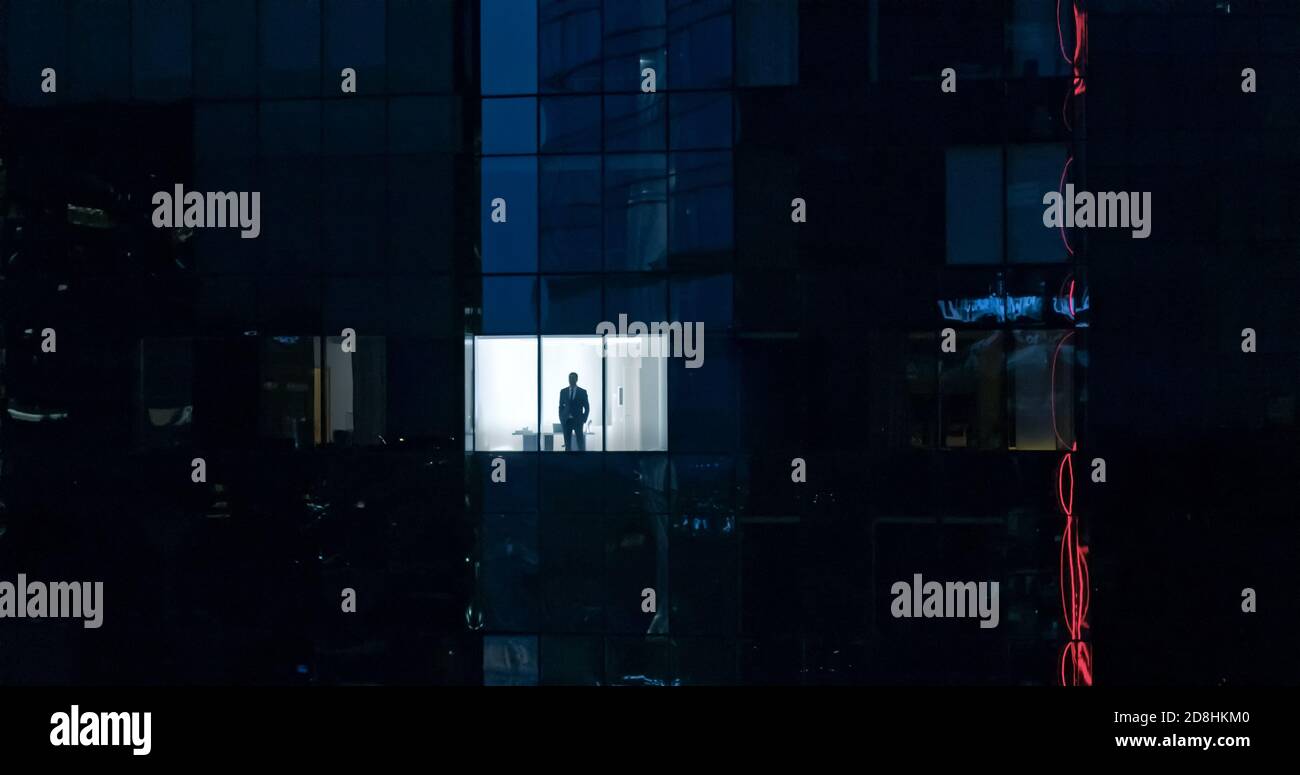 Luftaufnahme: Von draußen ins Bürogebäude mit Geschäftsmann, der aus dem Fenster schaut. Schöne Aufnahme des Finanzgeschäftsviertels Stockfoto