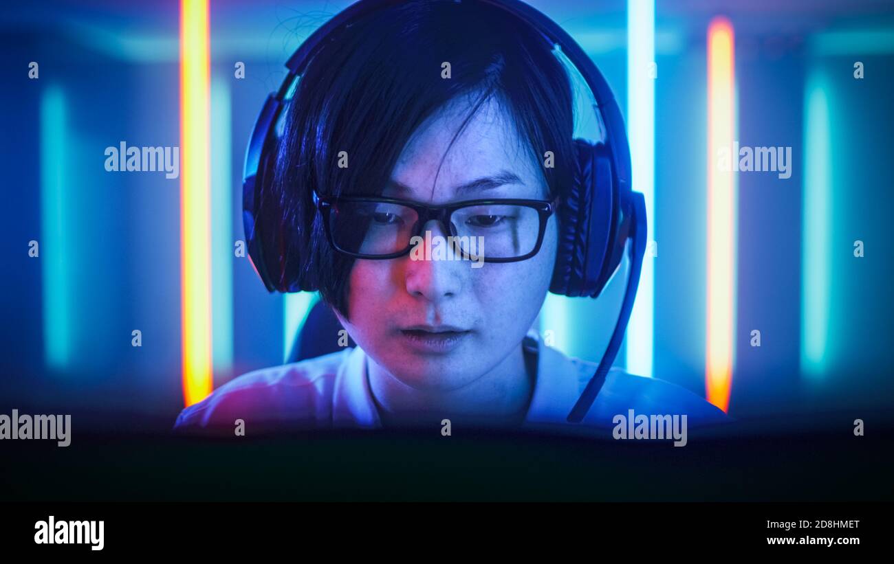 Professionelle Ostasiatische Gamer spielen in Online-Video-Spiel auf seinem Computer. Gespräche mit seinem Team über Mikrofon. Zimmer mit Neonlicht Stockfoto