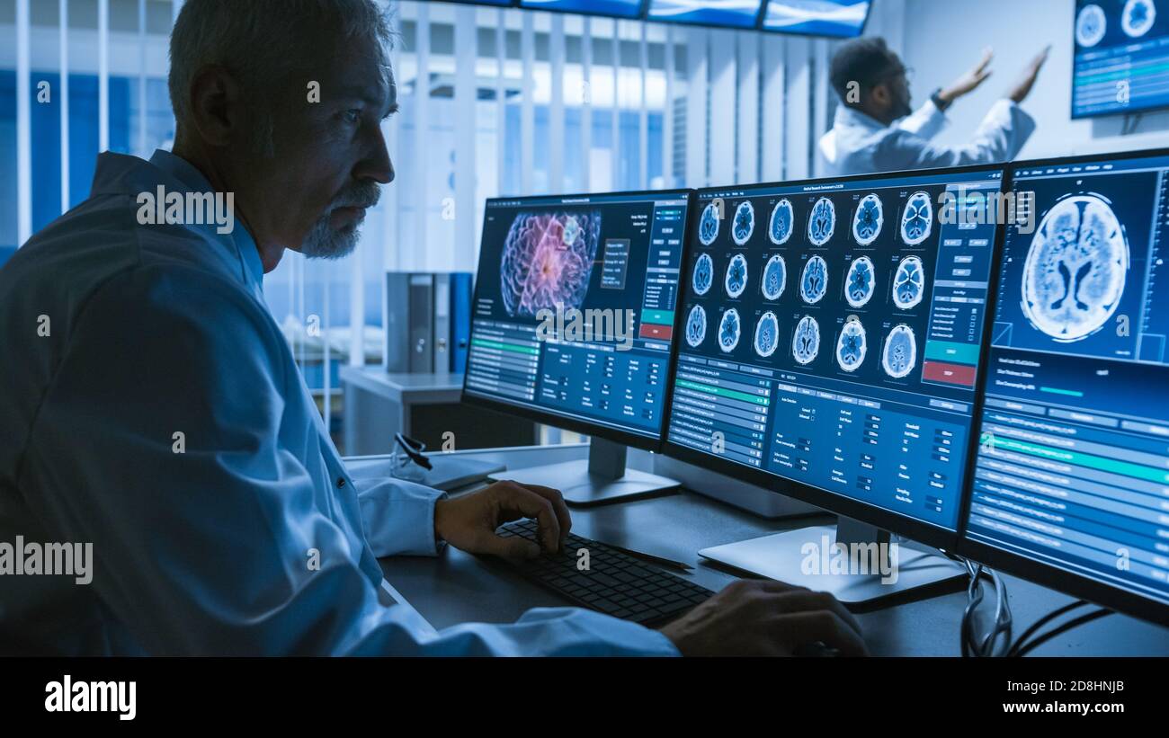 Über die Schulter Aufnahme von Senior Medical Scientist arbeiten mit CT Brain Scan-Bilder auf einem Personal Computer im Labor. Neurologen in der Forschung Stockfoto