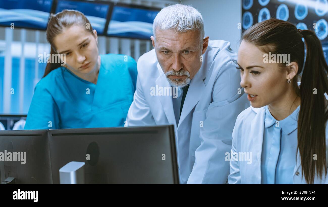 Diverse Team von Medizinern lösen Probleme und zeigen auf Computer-Bildschirme zeigt CT, MRI-Scans. Neurologen Neurowissenschaftler arbeiten im Gehirn Stockfoto