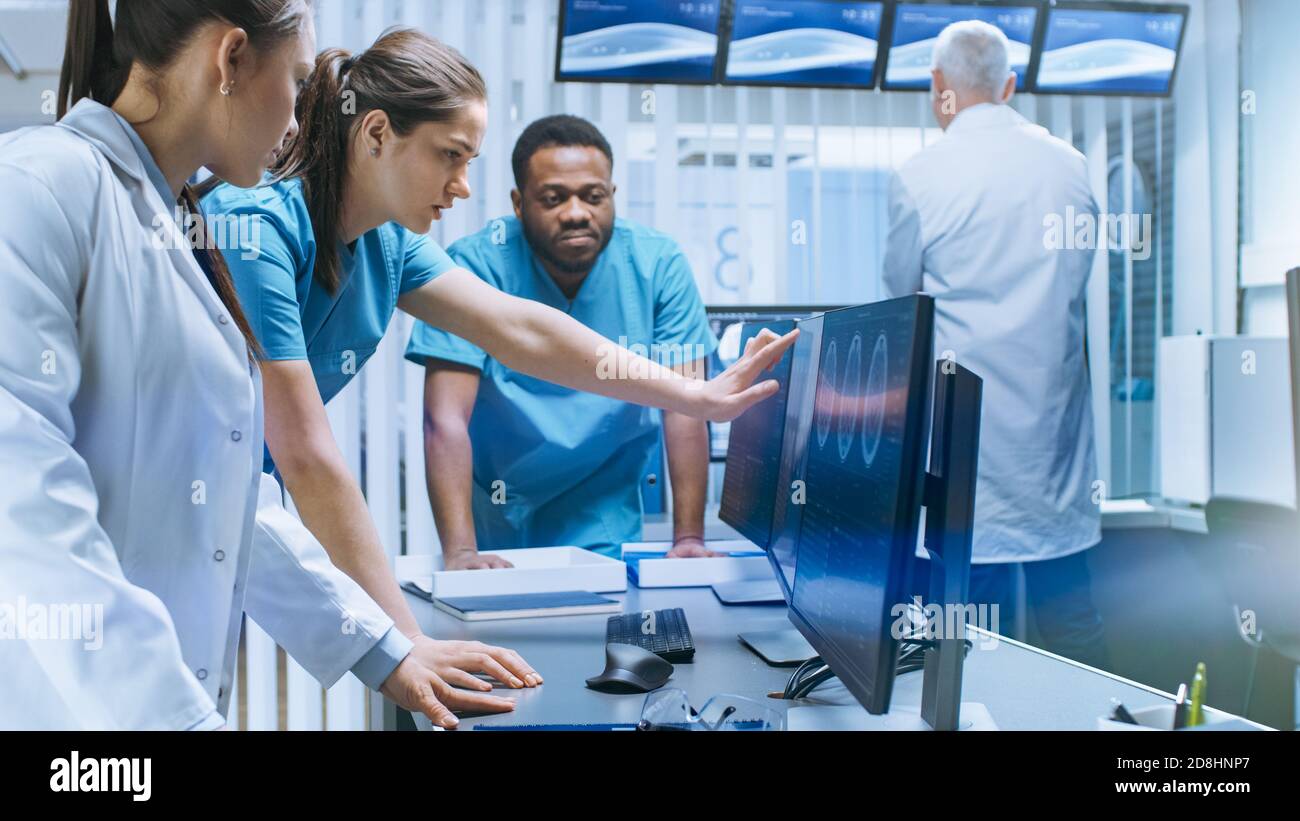 Diverse Team von Medizinern lösen Probleme und zeigen auf Computer-Bildschirme zeigt CT, MRI-Scans. Neurologen Neurowissenschaftler arbeiten im Gehirn Stockfoto