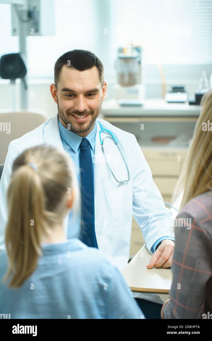 Mutter mit süßen kleinen Mädchen Besuch freundliche Kinderärztin. Der Arzt spricht mit ihnen nach einer gründlichen Untersuchung. Brightand Modern Medical Office. Stockfoto