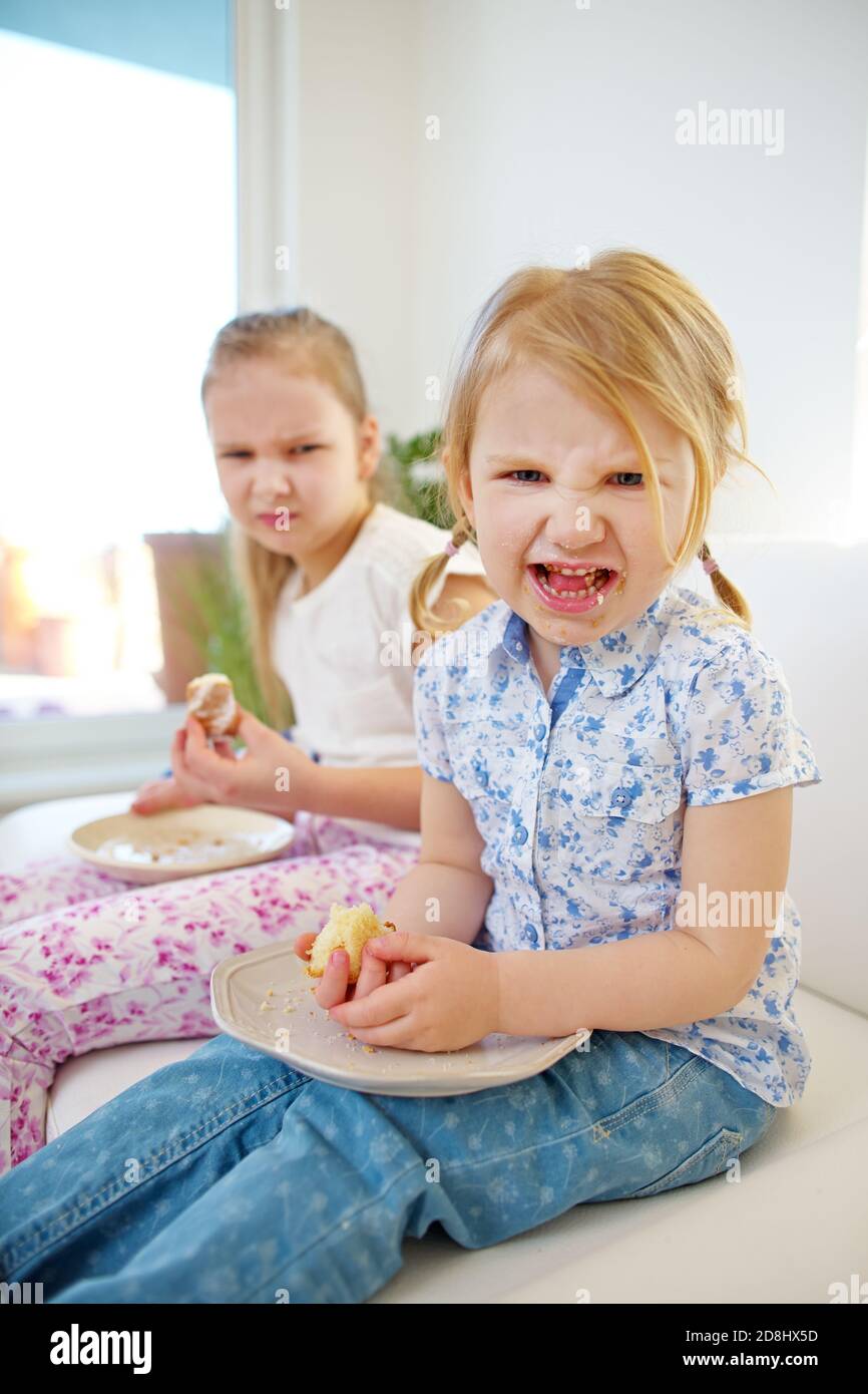 Zwei Kinder in schlechter Laune essen Kuchen und machen Verärgerte Gesichter Stockfoto