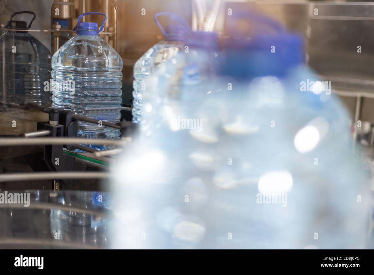 Abfüllanlage - Wasserabfüllanlage zur Verarbeitung und Abfüllung von reinem Quellwasser in blaue Flaschen. Selektiver Fokus. Stockfoto