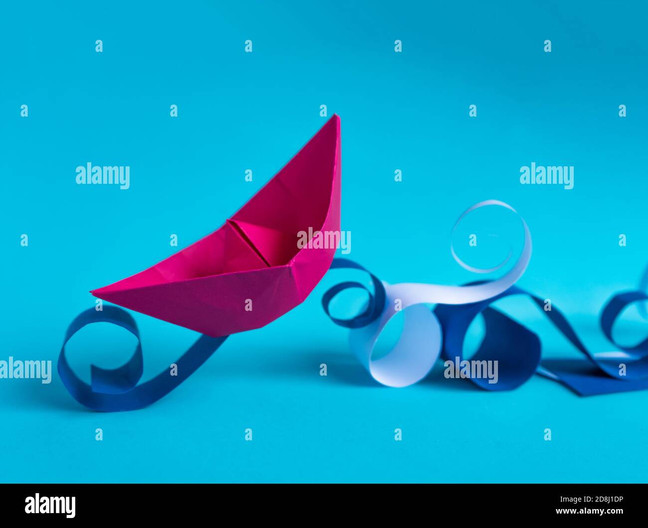 Rosa Papier Boot Navigation auf Papier Wellen auf hellblauem Hintergrund. Stockfoto