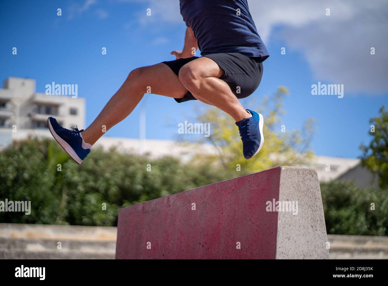 Mann trainiert hohe Leistung springt über ein Hindernis in der Mitten in einem Hof Stockfoto