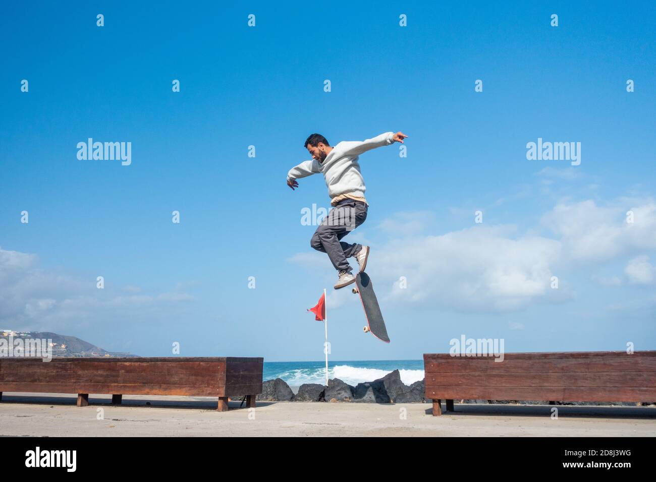 Las Palmas, Gran Canaria, Kanarische Inseln, Spanien. Oktober 2020. Ein Skateboarder schwänzt, als er versucht, über die Lücke zwischen den Bänken zu springen, die den Stadtstrand von Las Palmas auf Gran Canaria überblicken. Britische Touristen, die von den Kanarischen Inseln zurückkehren, müssen sich nicht mehr selbst isolieren. Die Kanarischen Inseln sind die einzige Region Spaniens, die vom neuen Ausnahmezustand befreit ist, den die spanische Regierung am Sonntag angekündigt hat. Oktober. Kredit: Alan Dawson/Alamy Live Nachrichten. Stockfoto