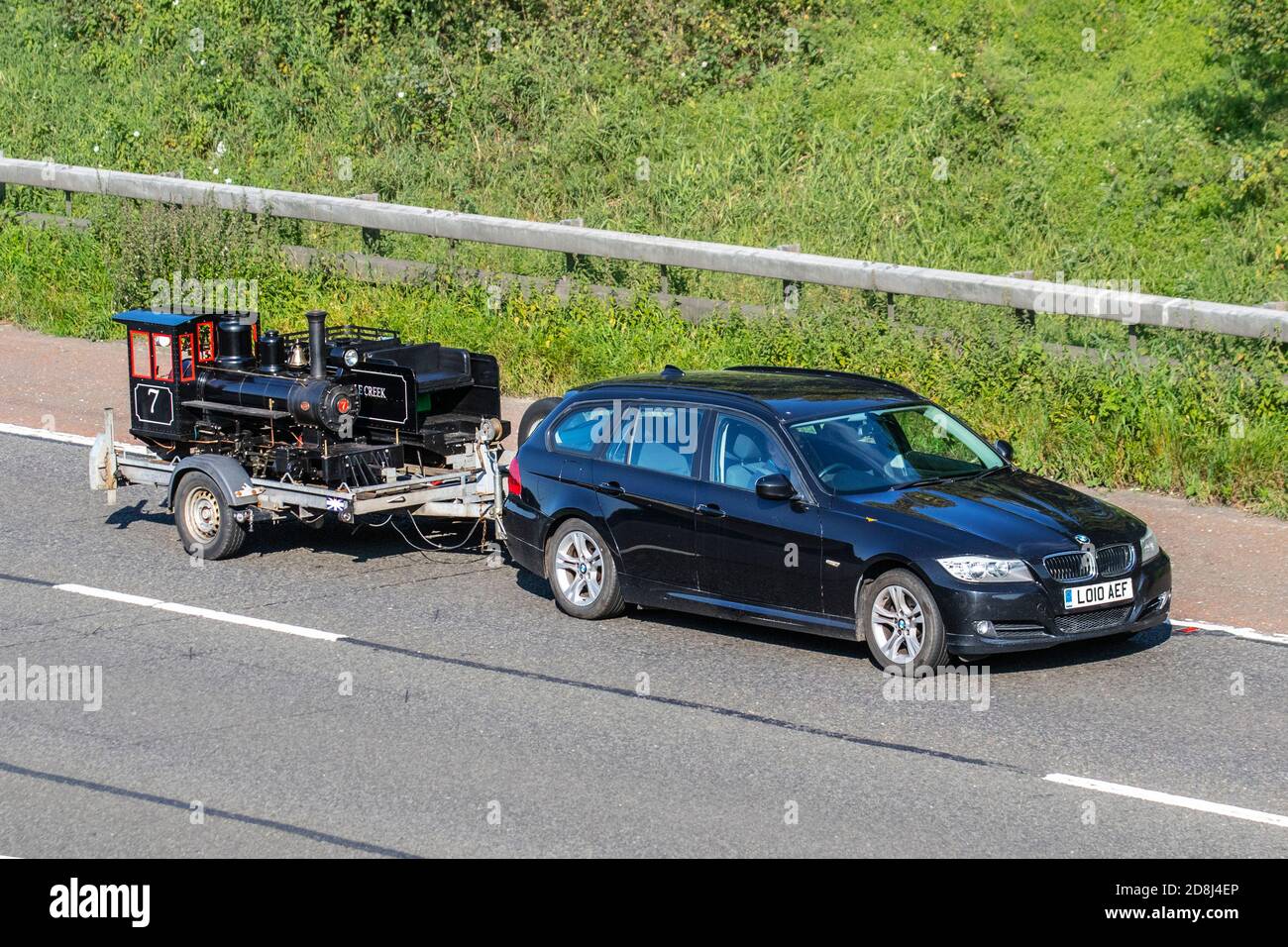 2010 schwarz BMW 318d Es 1995cc Diesel Nachlass Schleppen Miniatur-Modell Eisenbahn Dampfzug auf Anhänger; Fahrzeugverkehr, Fahrzeuge bewegen, Autos, Fahrzeug fahren auf britischen Straßen, Motoren, Fahren auf der Autobahn M61 Autobahn UK Straßennetz. Stockfoto