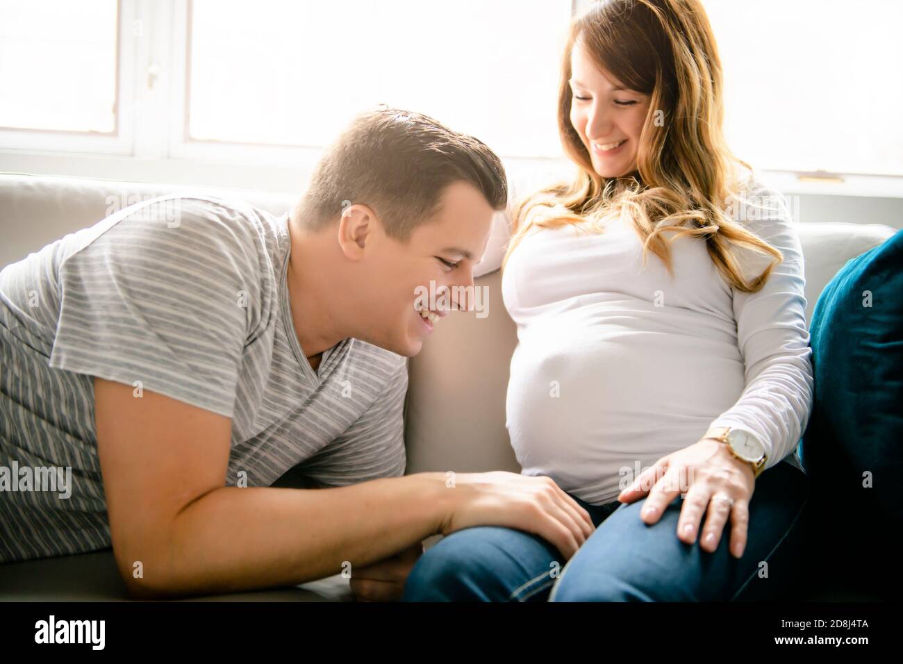 Glücklicher Mann mit schwangerer Frau auf der Couch sitzen Stockfoto