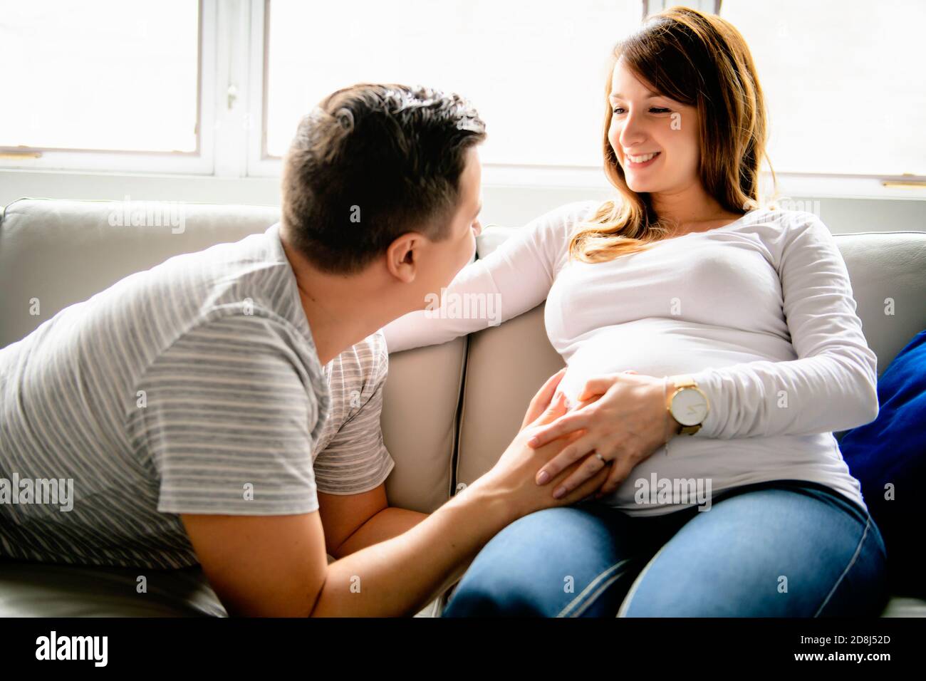 Glücklicher Mann mit schwangerer Frau auf der Couch sitzen Stockfoto